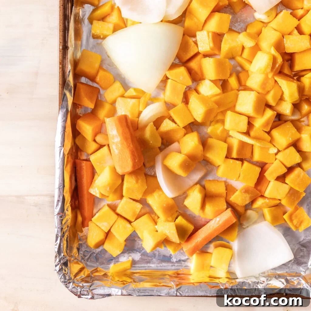Creamy Butternut Squash and Carrot Soup Recipe for Fall 4 chopped butternut squash, carrot, onion, and garlic on a foil lined sheet pan