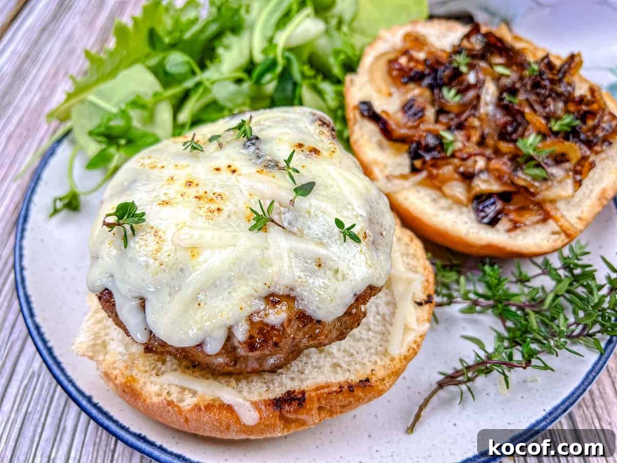 39 Outdoor Grilling Dinners That Make You Ditch the Oven Tonight 17 Close-up shot of Grilled French Onion Pork Burgers on a Ninja Woodfire Outdoor Grill topped with cheesy onion on a plate.