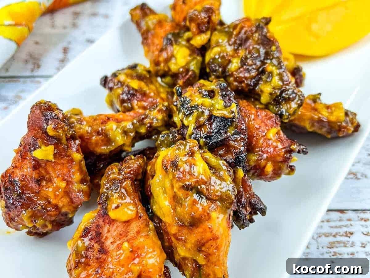 39 Outdoor Grilling Dinners That Make You Ditch the Oven Tonight 18 A plate of chicken wings on a white plate with a slice of mango.