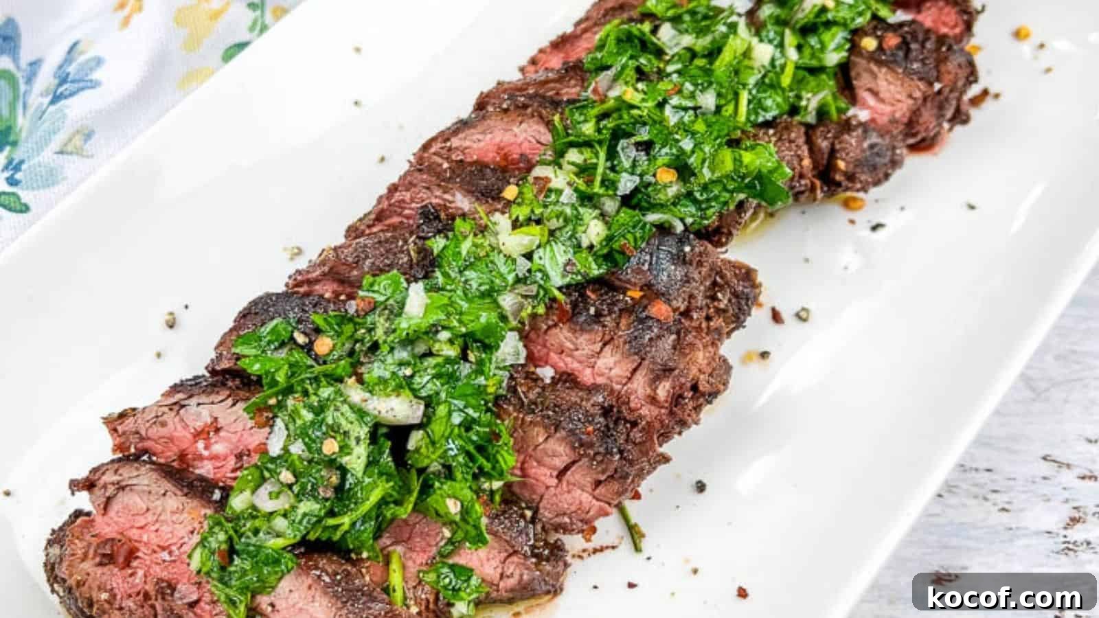 39 Outdoor Grilling Dinners That Make You Ditch the Oven Tonight 33 A plate of sliced Grilled Hanger Steaks with Chimichurri, served on a white rectangular dish.