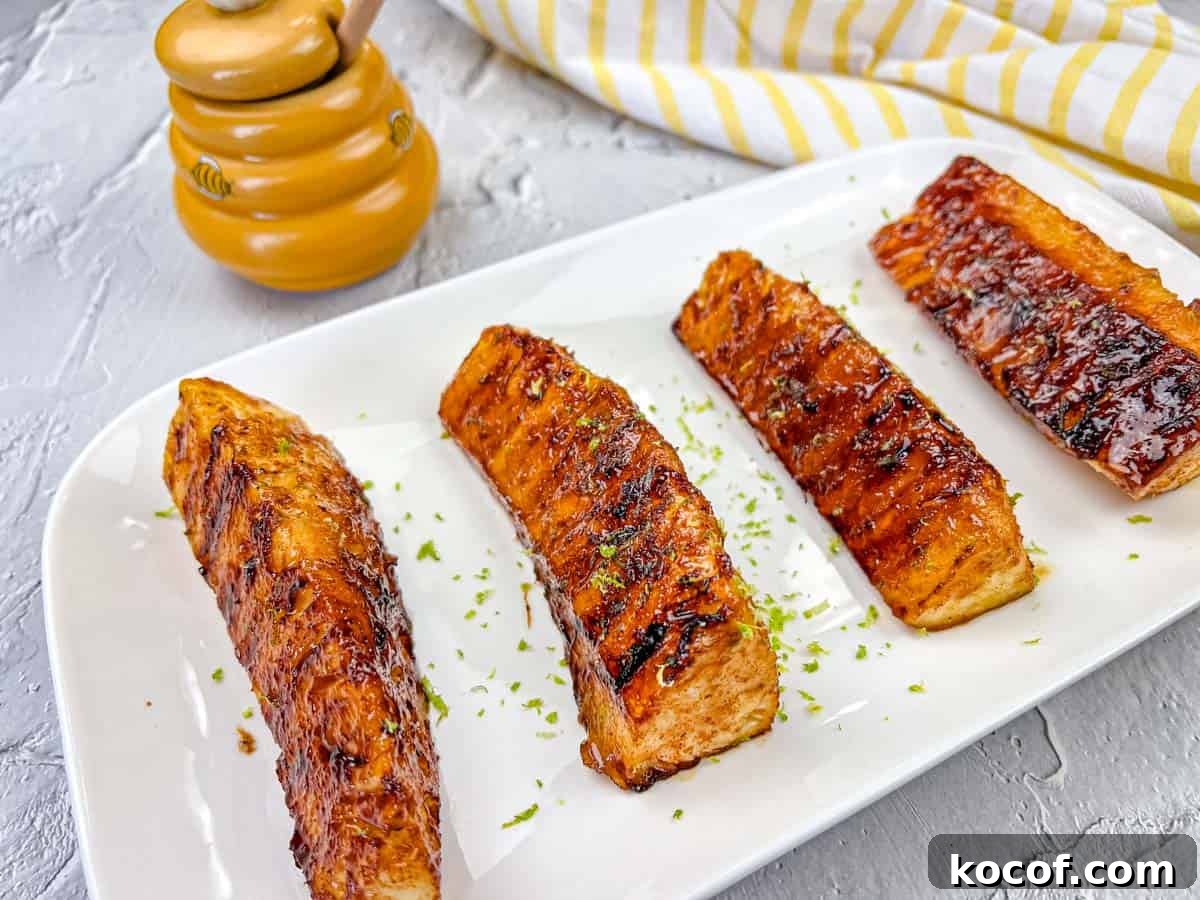 39 Outdoor Grilling Dinners That Make You Ditch the Oven Tonight 5 Four pieces of Grilled Pineapple With Buttery Lime Glaze on a white rectangular plate.