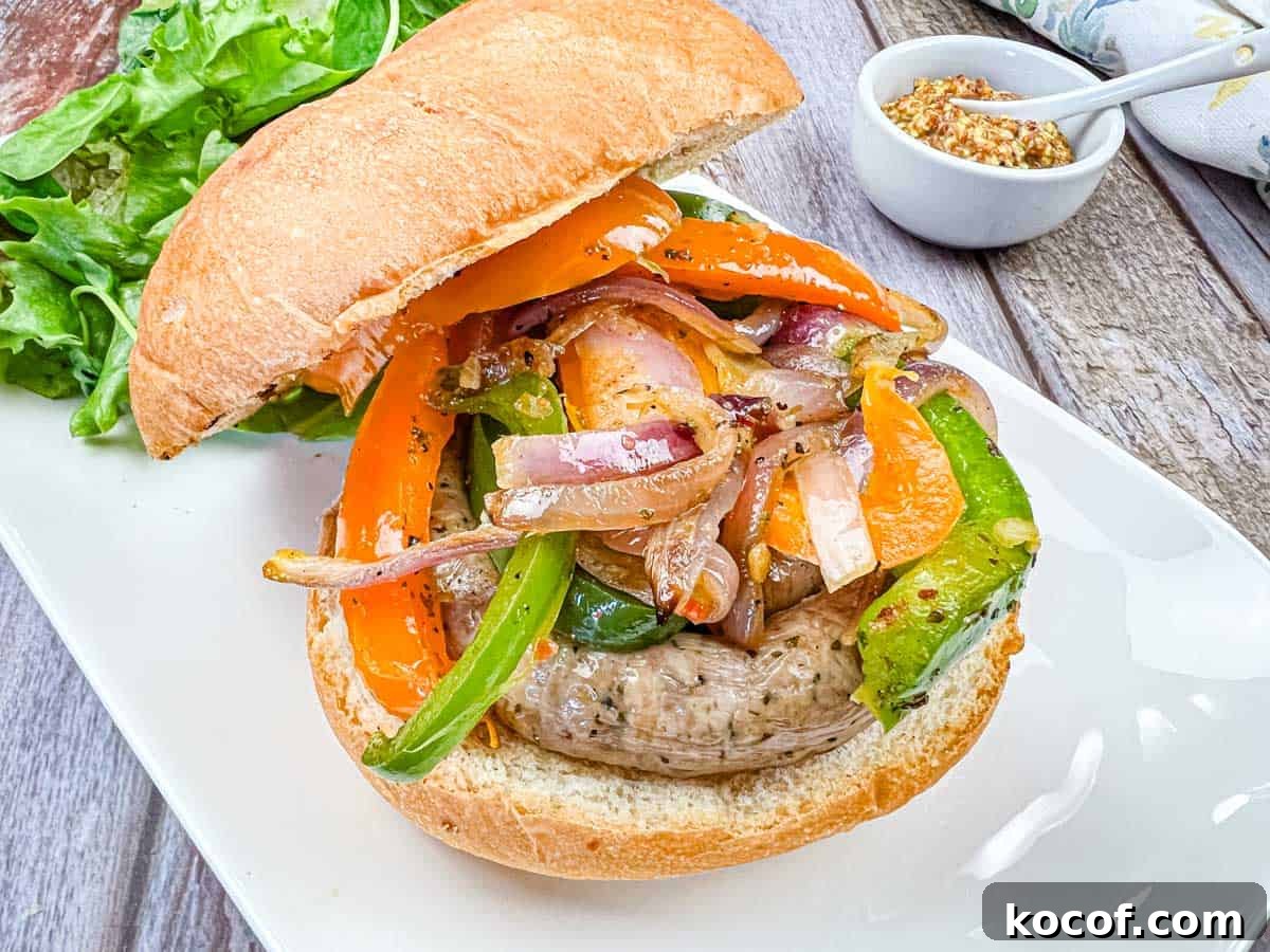 39 Outdoor Grilling Dinners That Make You Ditch the Oven Tonight 7 A sandwich with grilled sausage & peppers, and onions on a plate.