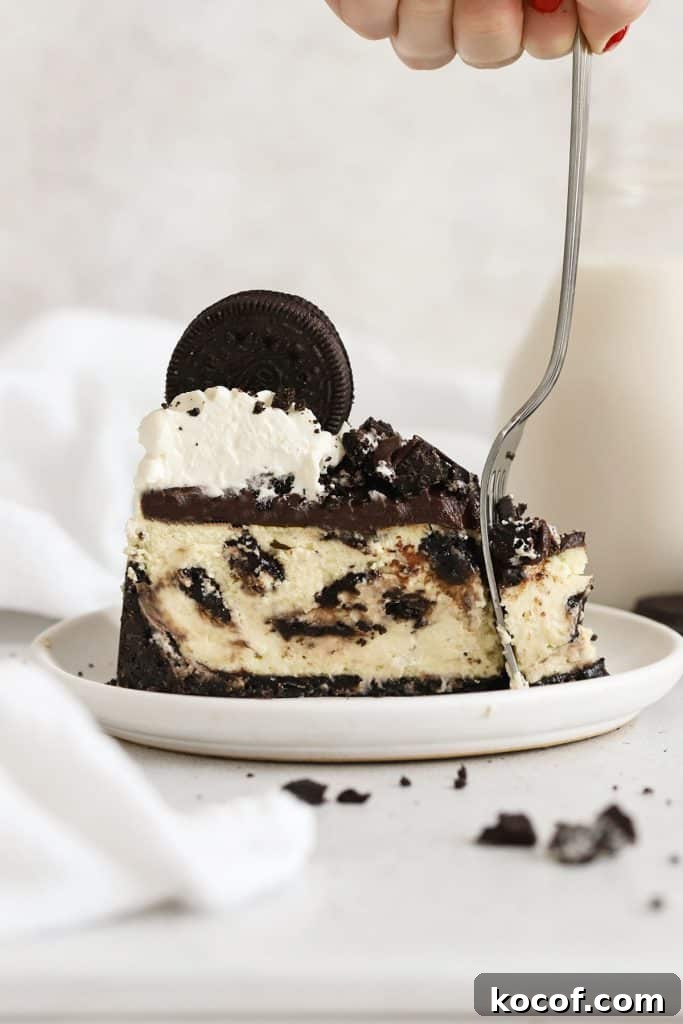 Gluten-Free Strawberry Cheesecake Recipe with Fresh Berry Topping 10 fork cutting into a slice of gluten-free Oreo cheesecake on a white plate