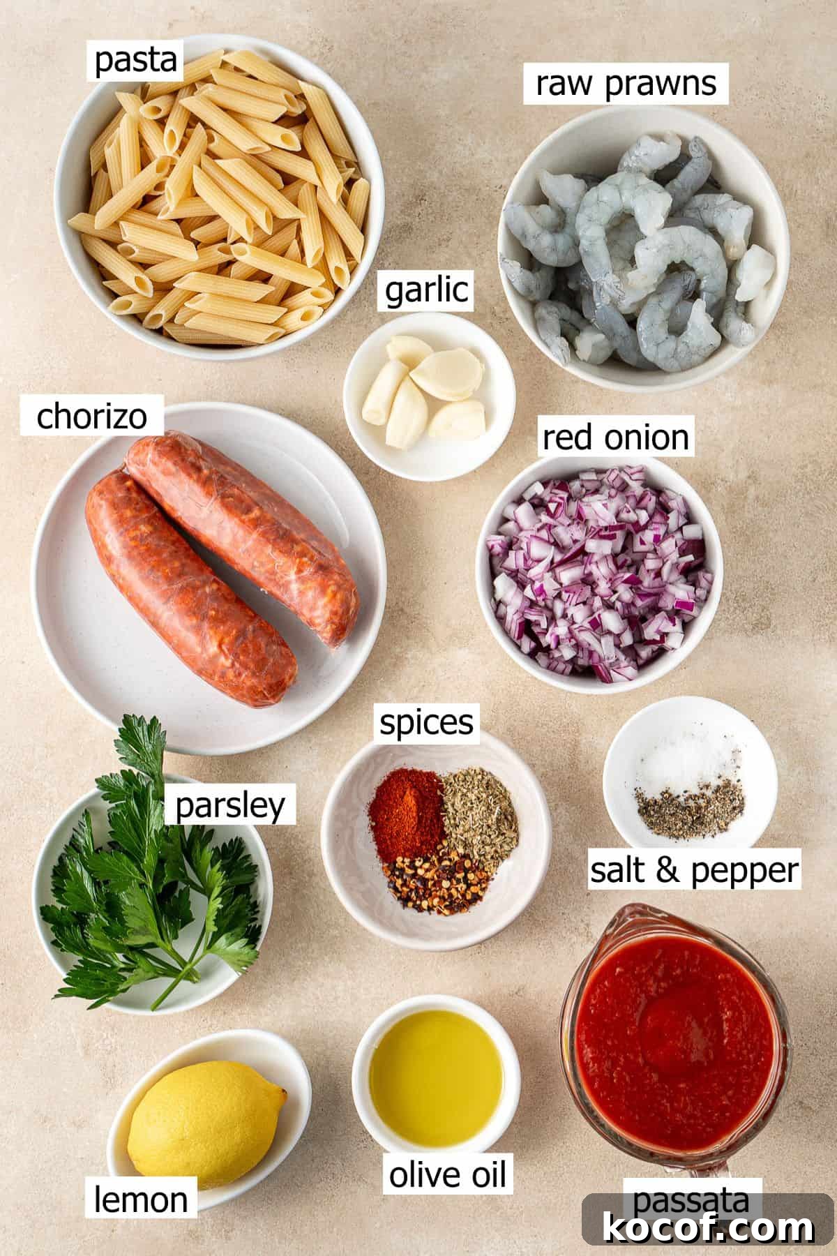 All ingredients needed to make prawn and chorizo pasta laid out in small bowls.