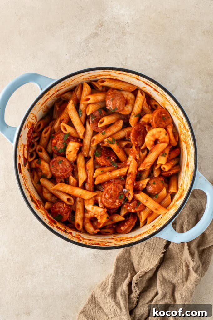 The cooked pasta added into the pot with the sauce.
