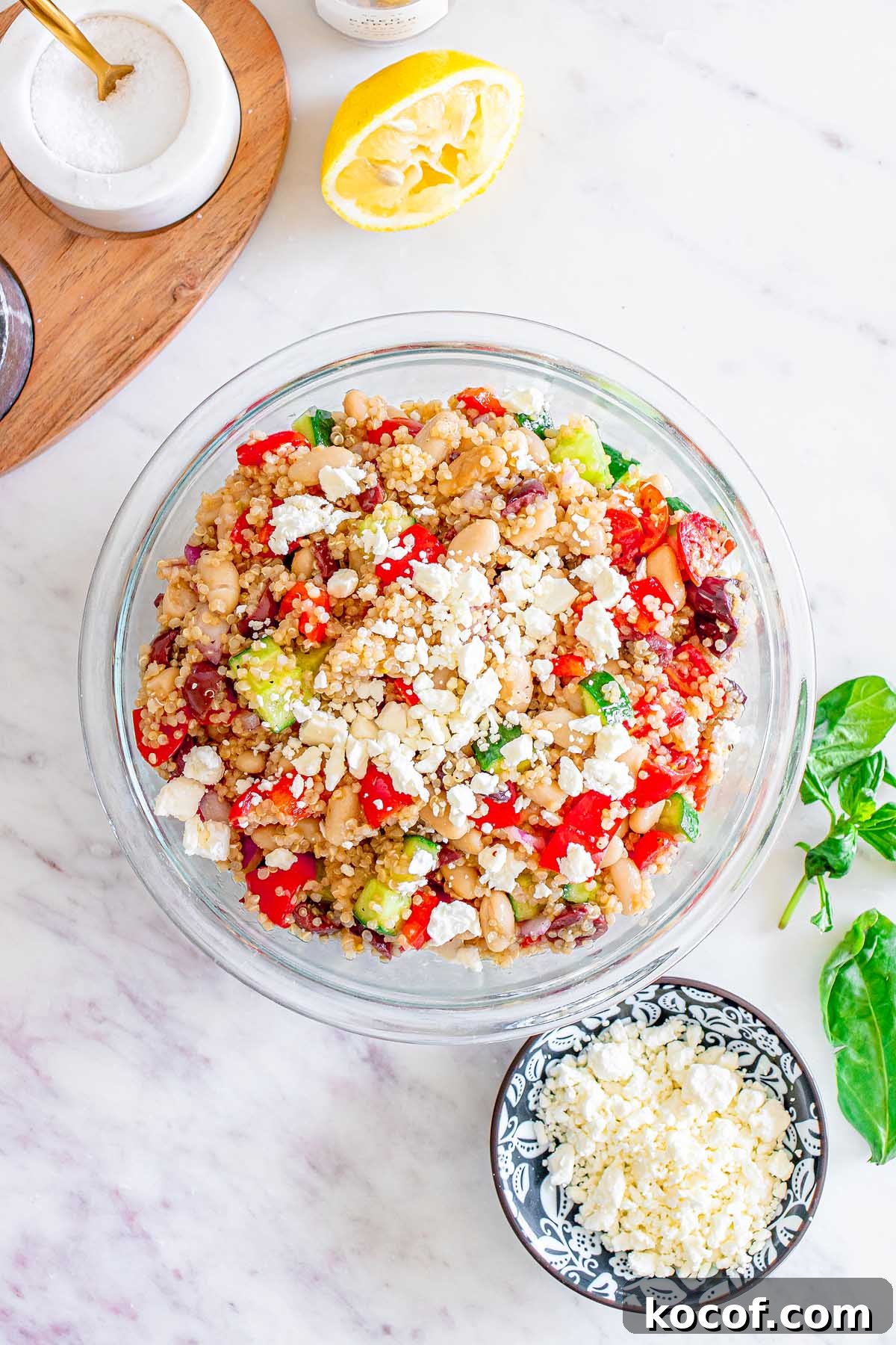 Mediterranean Quinoa Salad with Feta, Cucumbers & Olives 17 A bowl of Mediterranean Quinoa Salad topped with crumbled feta, served alongside a small bowl of extra feta and fresh spinach.