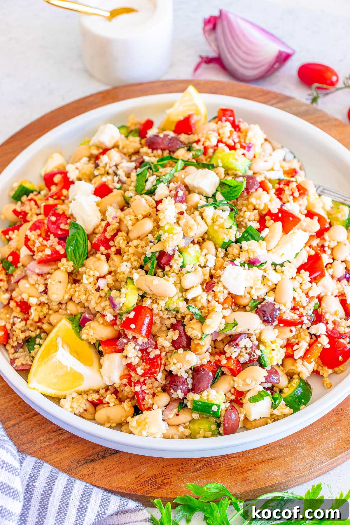 Mediterranean Quinoa Salad with Feta, Cucumbers & Olives 18 A colorful Mediterranean Quinoa Salad with beans, feta, tomatoes, cucumber, olives, and lemon wedges on a white plate.