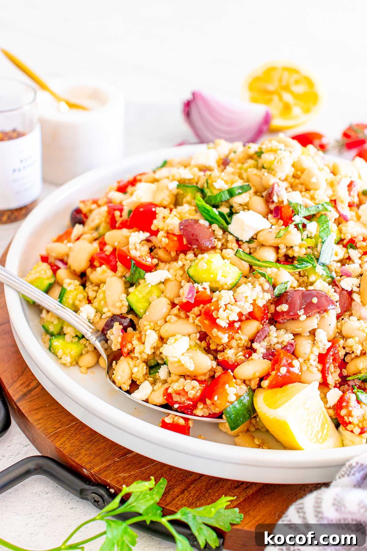 Mediterranean Quinoa Salad with Feta, Cucumbers & Olives 3 A plate of Mediterranean Quinoa Salad with white beans, tomatoes, cucumber, olives, fresh herbs, and lemon wedges.