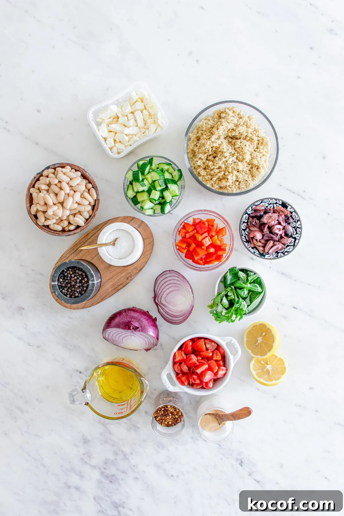 Mediterranean Quinoa Salad with Feta, Cucumbers & Olives 5 Ingredients for a Mediterranean Quinoa Salad arranged on a white surface, including quinoa, veggies, beans, cheese, and seasonings.