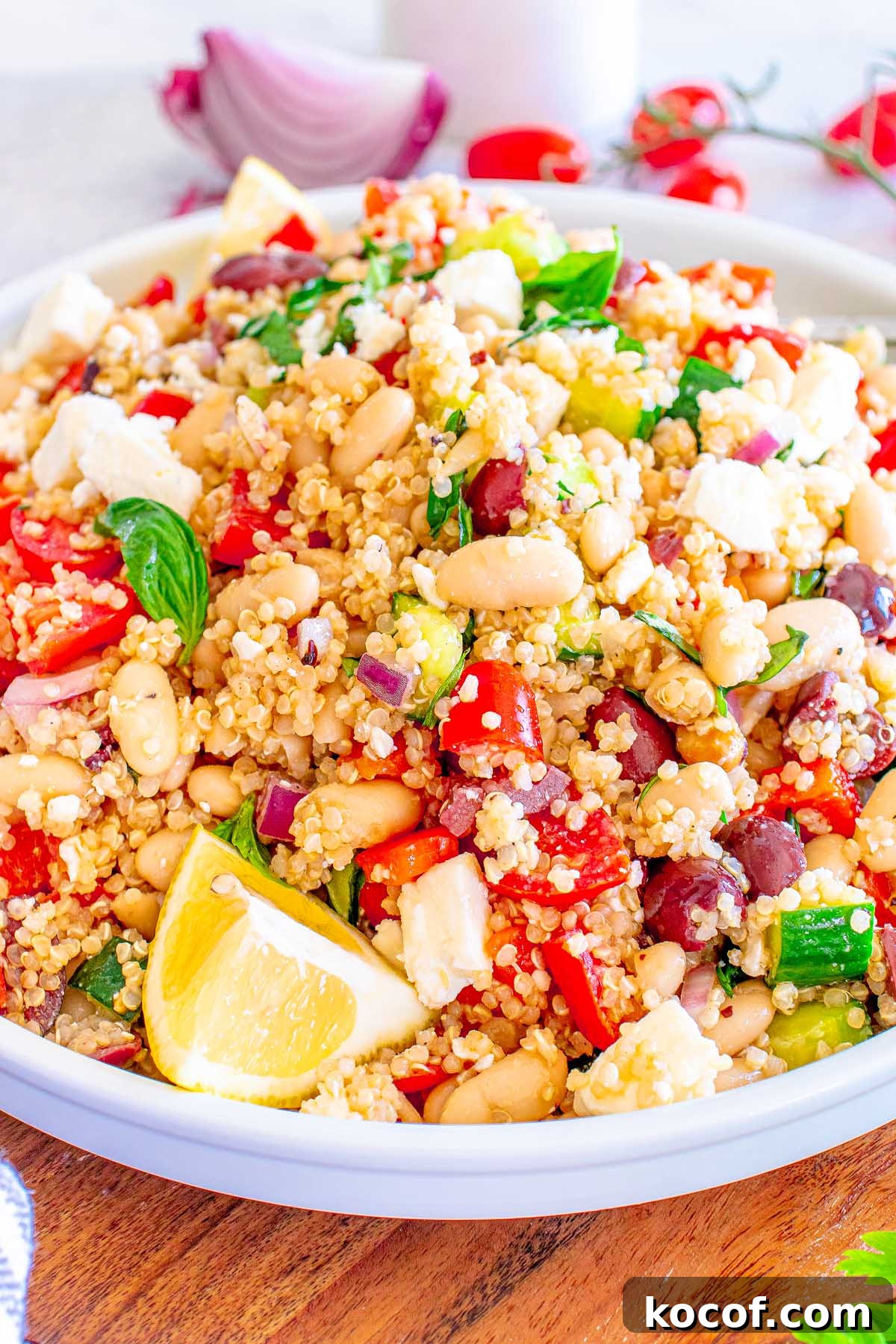 Mediterranean Quinoa Salad with Feta, Cucumbers & Olives 8 A bowl of Mediterranean Quinoa Salad with white beans, feta, tomatoes, cucumbers, olives, and a lemon wedge.