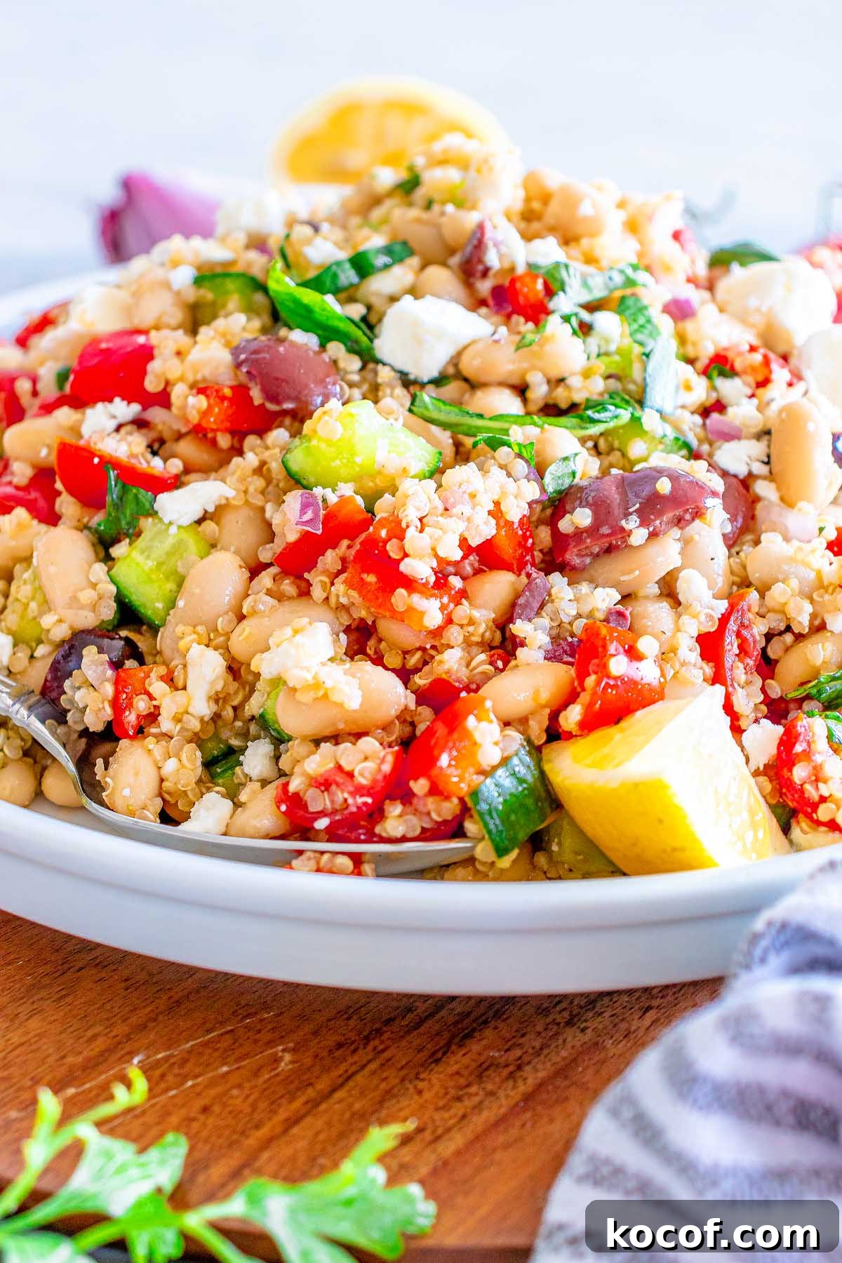 Mediterranean Quinoa Salad with Feta, Cucumbers & Olives 10 A close-up of a Mediterranean Quinoa Salad with beans, cucumbers, tomatoes, olives, and feta cheese on a white plate.