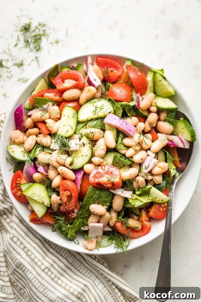 White bowl holding white bean cucumber tomato salad.