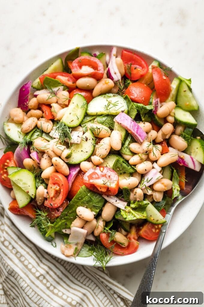 Close-up of white bean salad in a small white serving bowl.