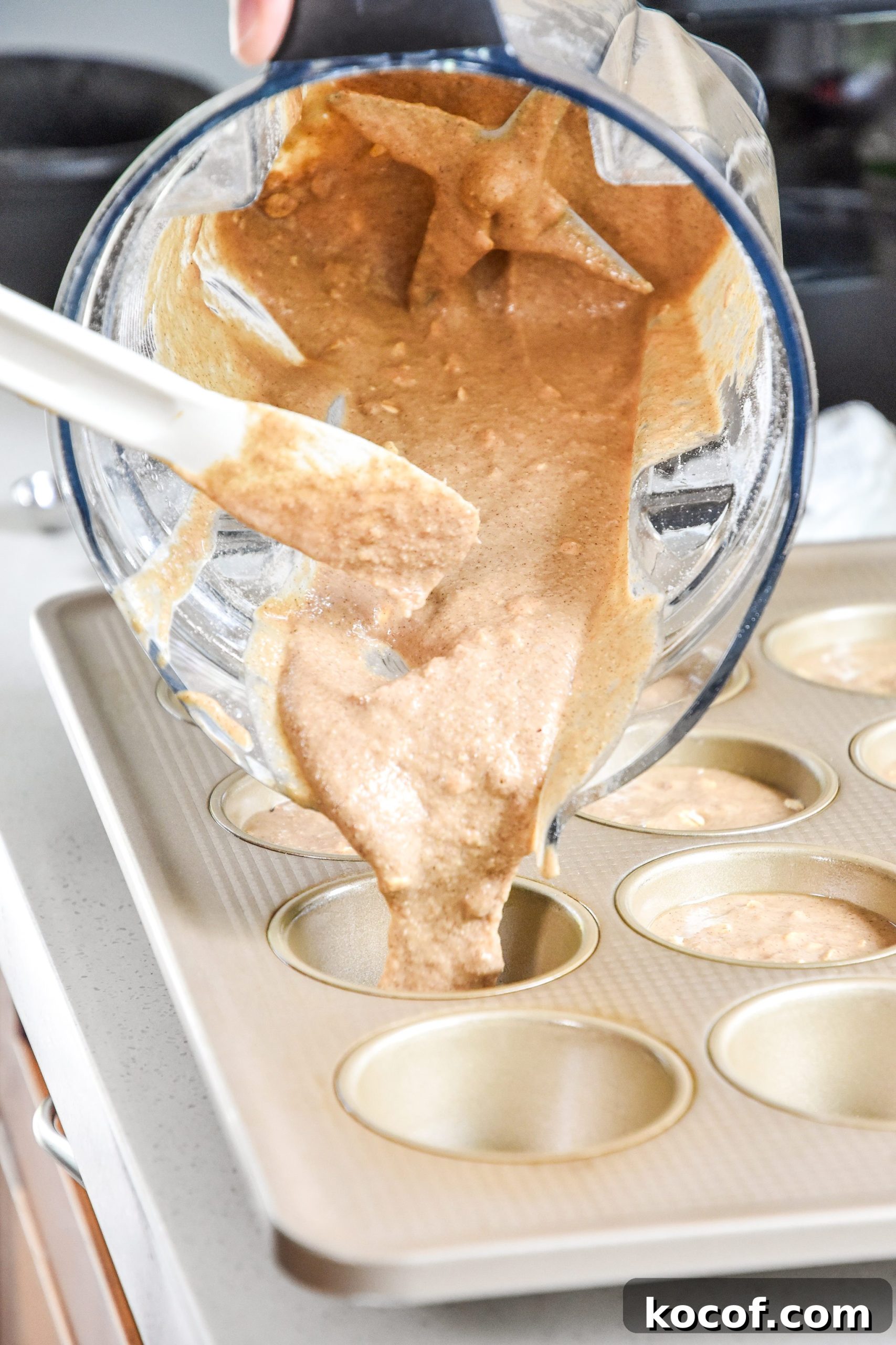 batter being poured into a muffin tin