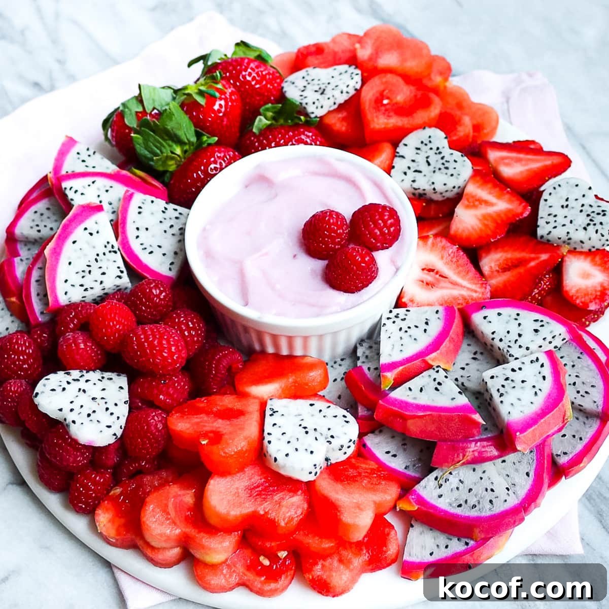 A fruit platter with fresh berries, melon, and dragon fruit with a small white dish filled with a homemade strawberry fruit dip.