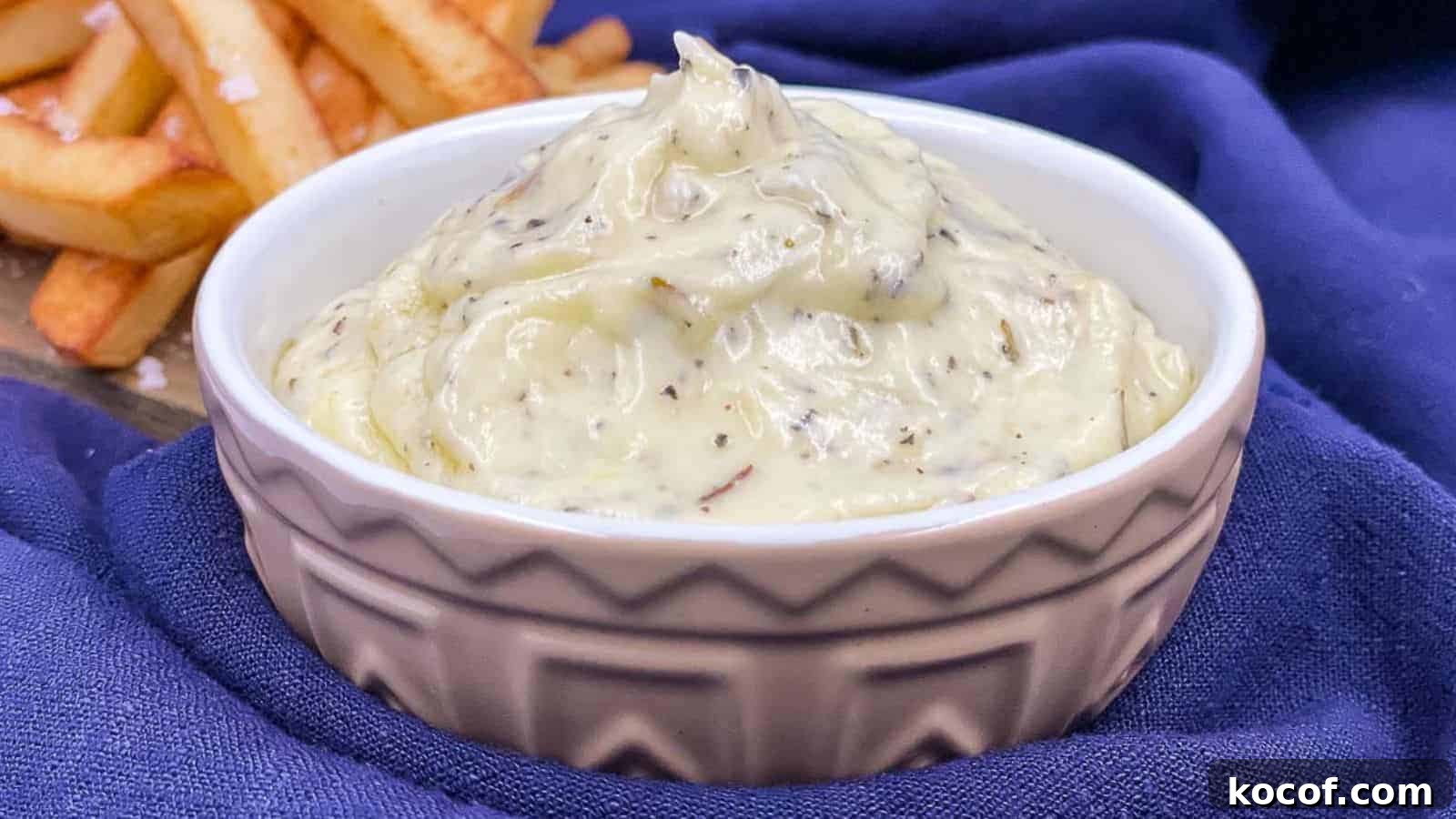 Garlic dip in a serving bowl with fries by it.