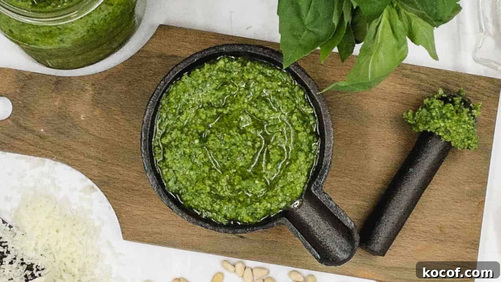 Homemade pesto in a cast iron dish with nuts and basil around it.