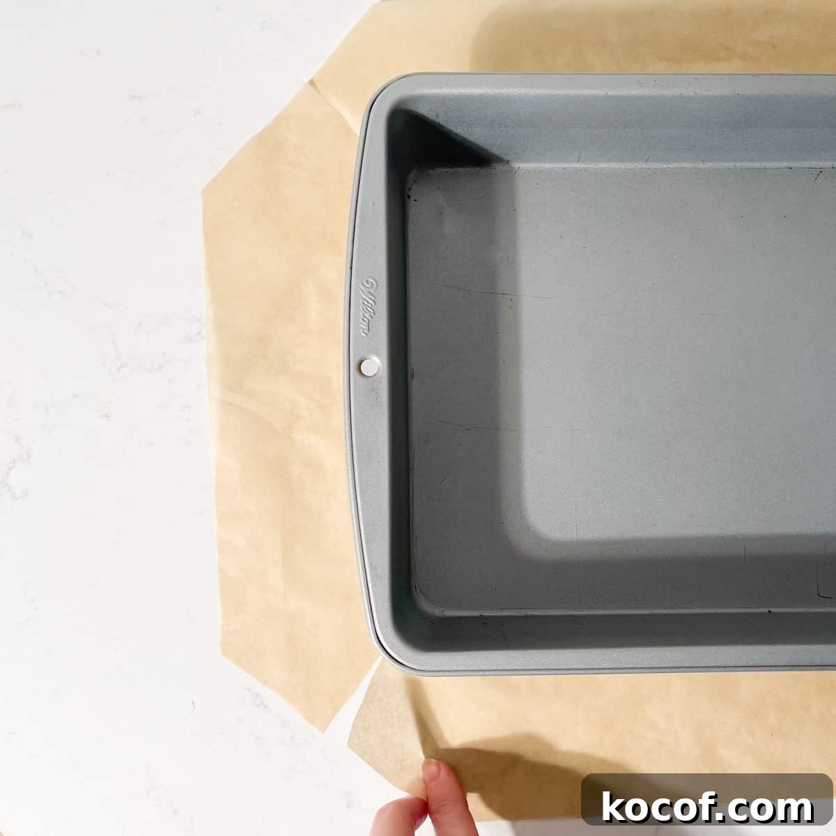 A baking tin on a piece of baking paper with slits cut into each corner of the paper to fit easily into the tin.