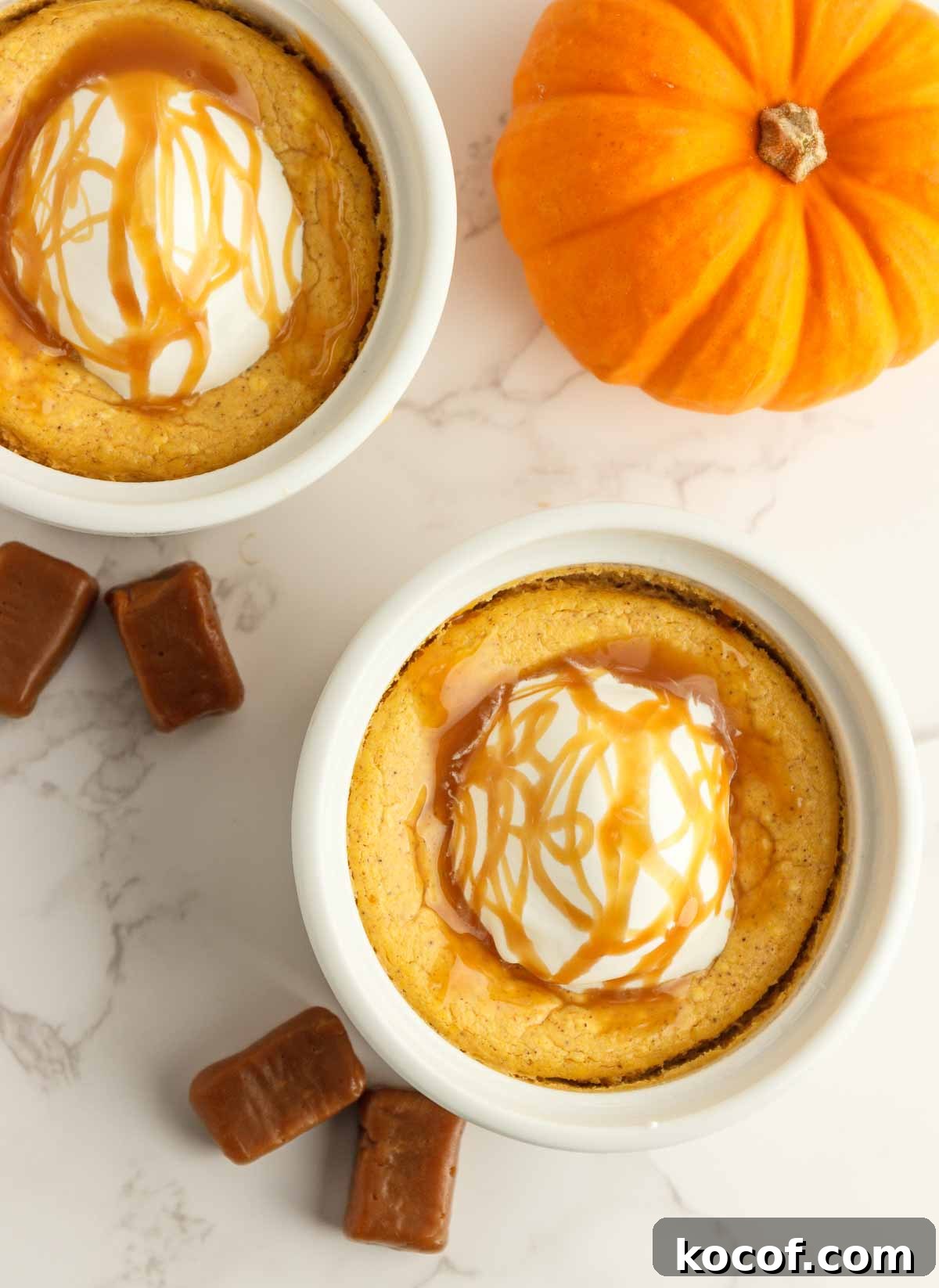 Two easy kettopumpkin cheesecakes in white ramekins with whipped cream and caramel syrup.
