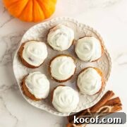 Keto pumpkin donut holes with white chocolate frosting on a white plate.