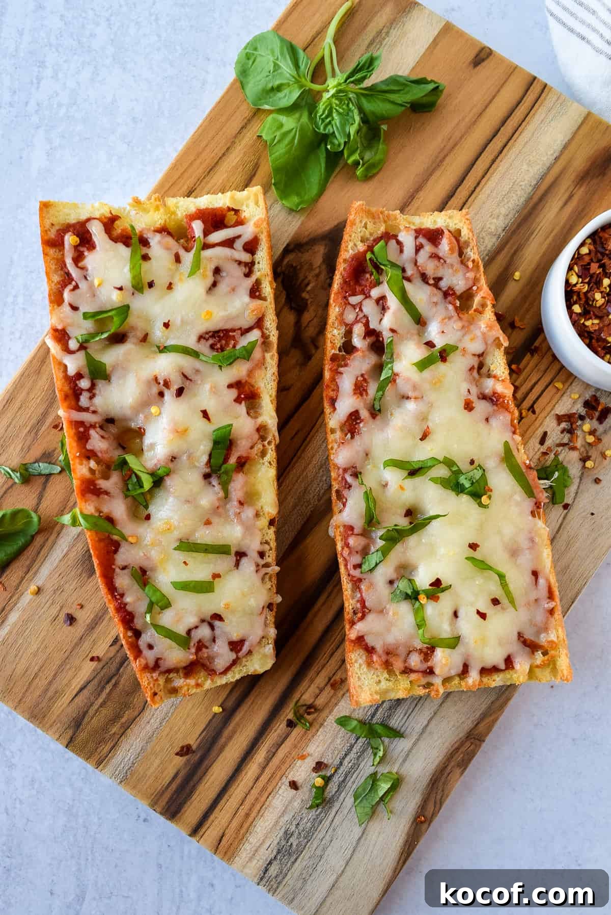 Air Fryer French Bread Pizza on a cutting board topped with basil.