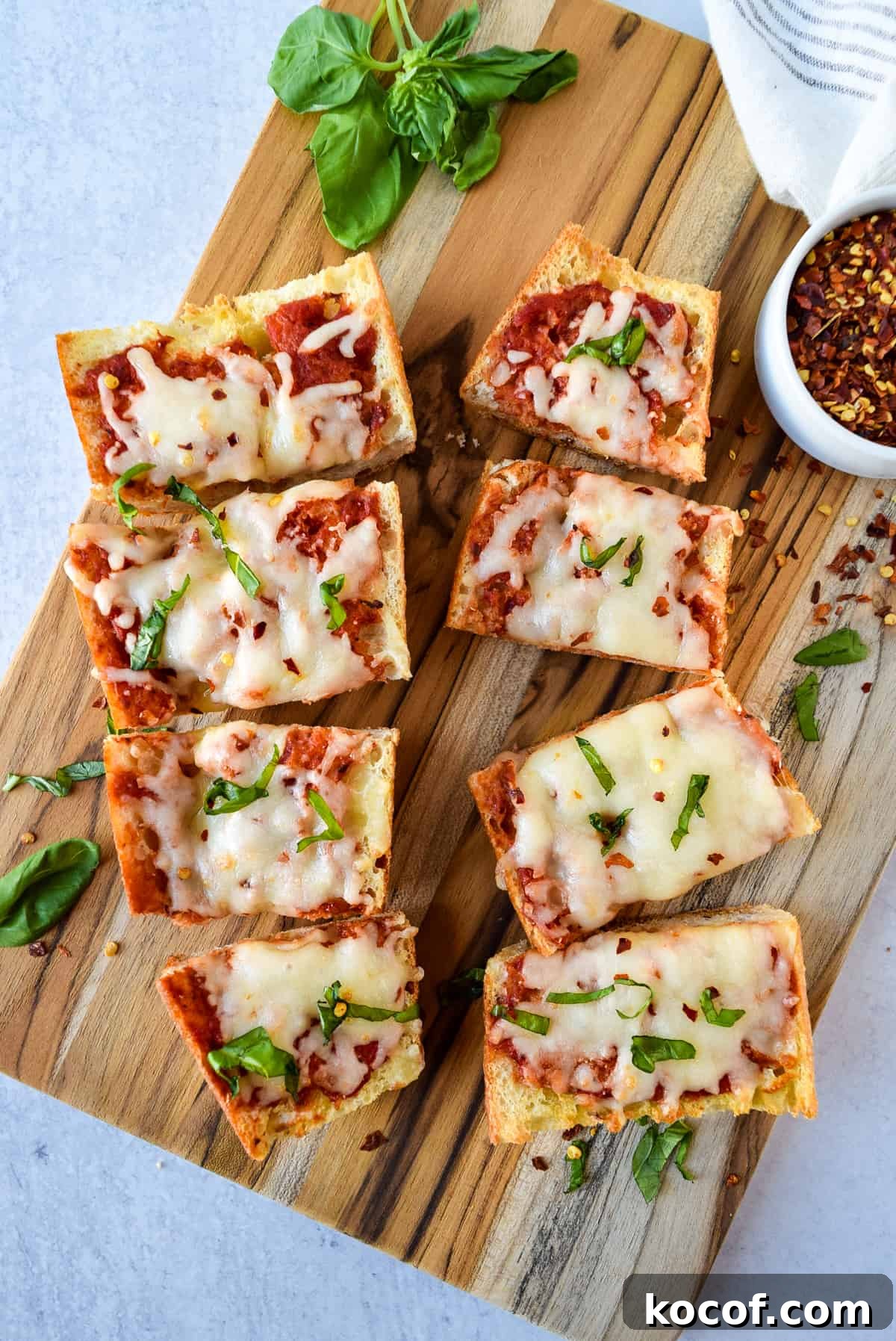 Air Fryer French Bread Pizza cut into 8 pieces on a cutting board.