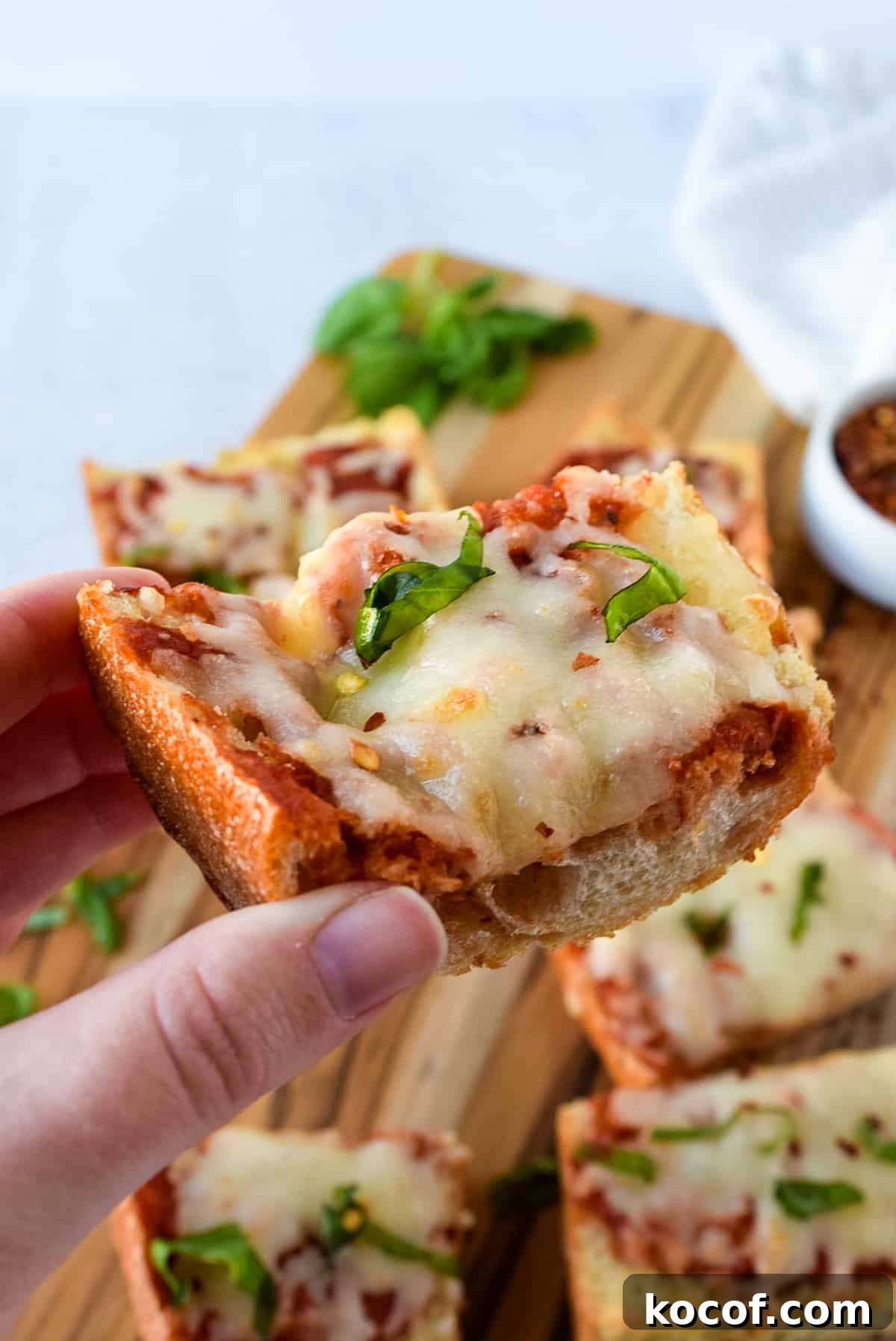 A hand holding a slice of Air Fryer French Bread Pizza.