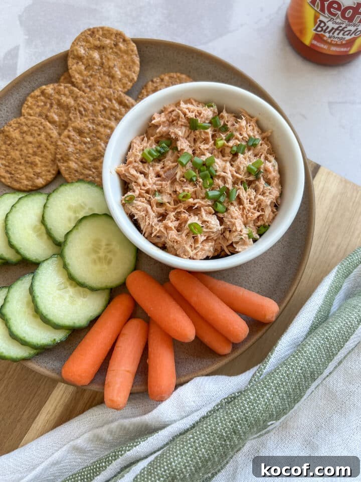 Buffalo tuna dip on a plate with crackers, cucumber slices, and carrot sticks