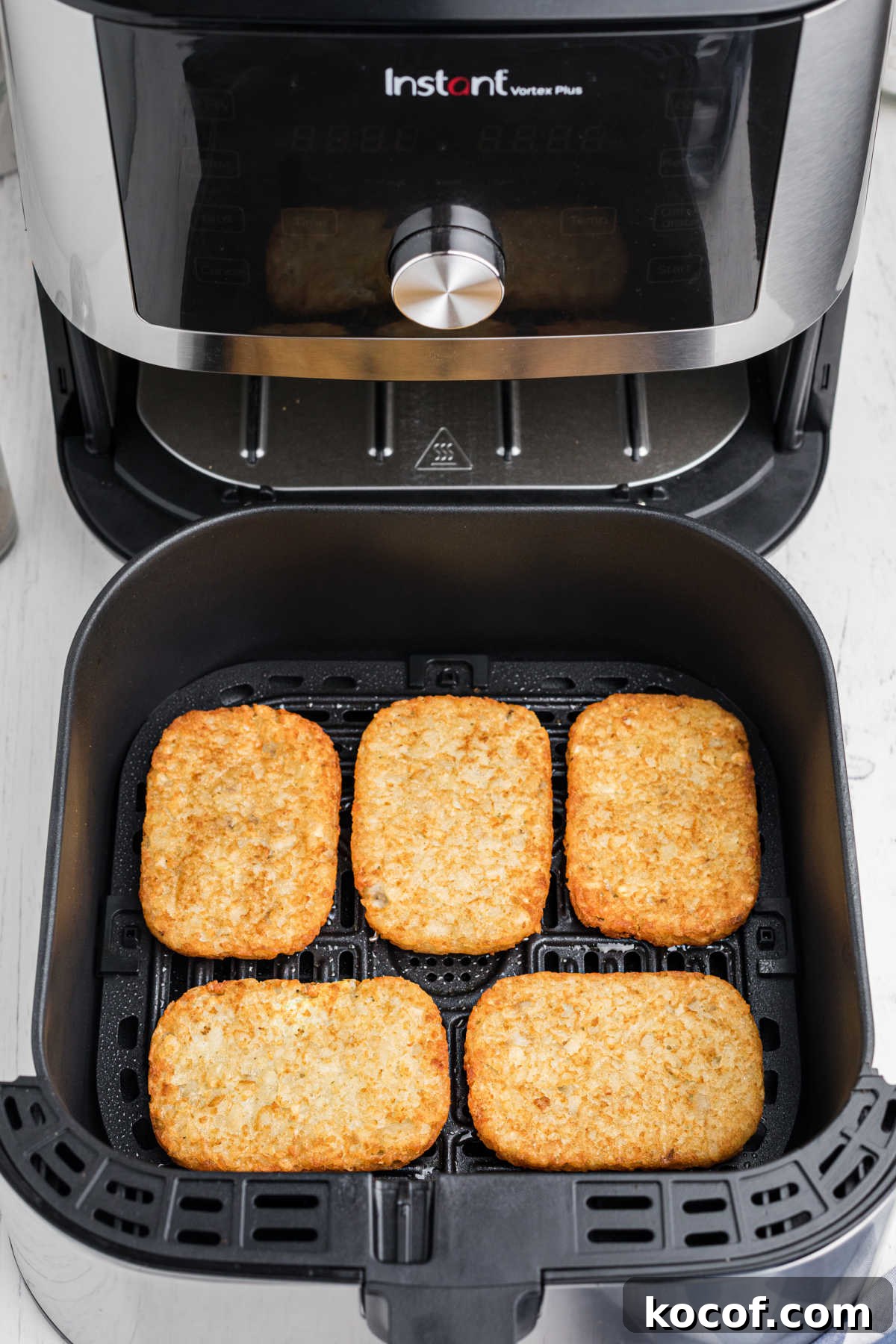 an open air fryer showing 5 hash browns cooked