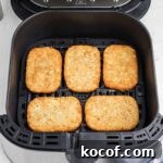 an air fryer basket with 5 hash brown patties lined up