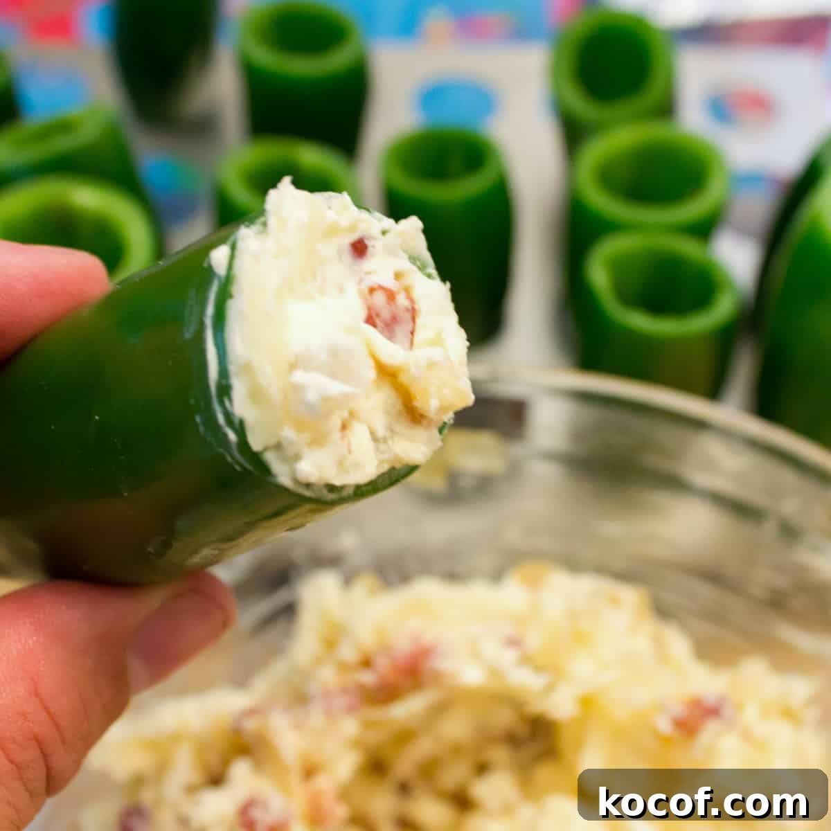 A cored jalapeño pepper being stuffed with a cream cheese and chorizo mixture.