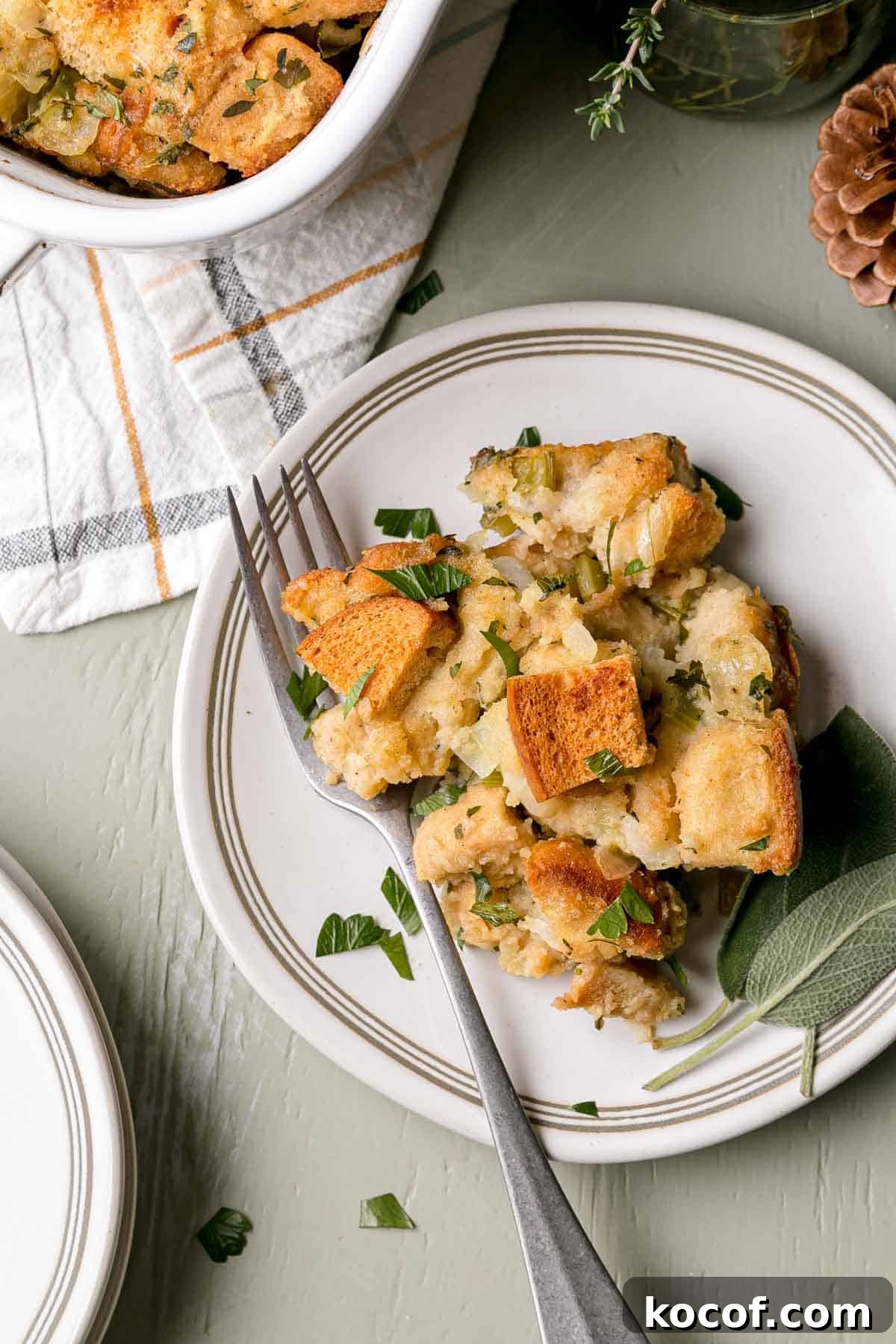 A serving of gluten-free stuffing on a small plate with a fork and sage leaves.
