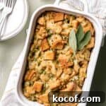 White Staub casserole dish with baked gluten free stuffing and sage leaves on top.