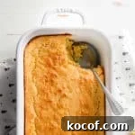 Gluten free corn casserole in white dish with scoop removed.