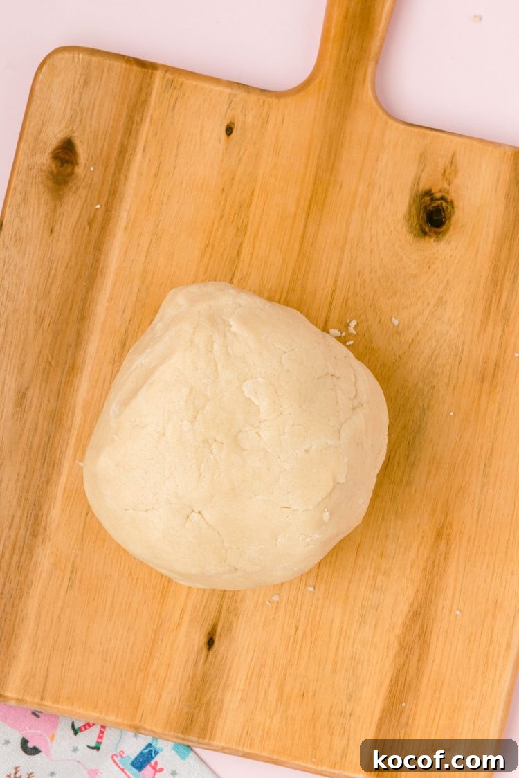 A ball of sugar cookie dough on a wooden board.