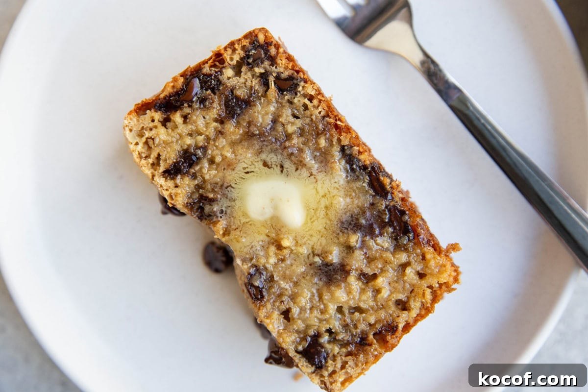 Slice of chocolate chip bread on a plate with melted butter on top.